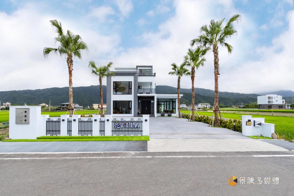 a house with palm trees in front of it at 亮Villa in Sanxing