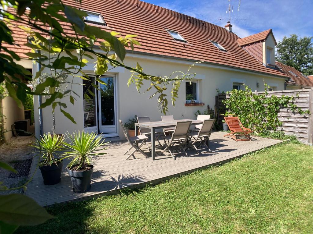 a wooden deck with a table and chairs in a yard at Une jolie maison climatisée pour vous reposer in Blois