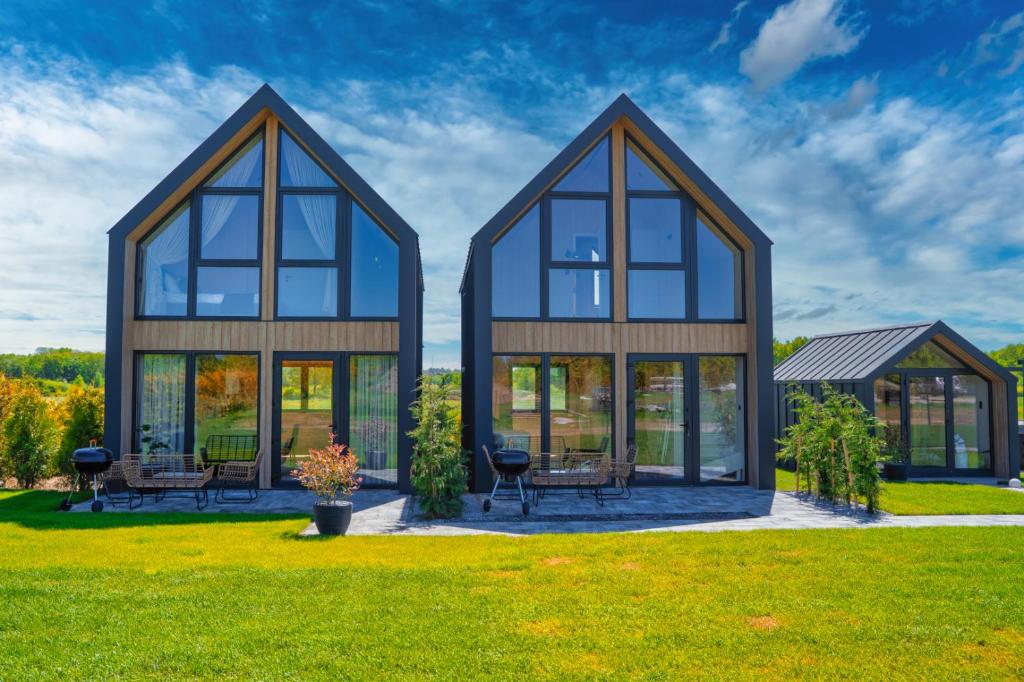 a house with large windows on a green lawn at Craftowe domki in Rusinowo