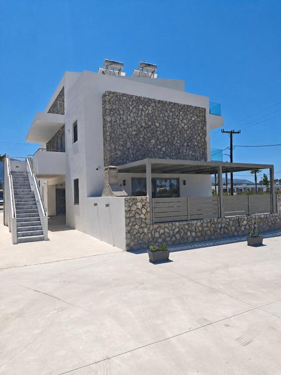 a large white building with a balcony and stairs at Salt & Light House in Tigaki