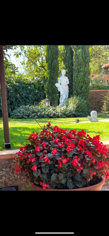 a pot of red flowers in front of a statue at Maria's Studios Rent Peplos in Péplos