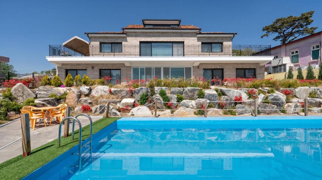 a house with a swimming pool in front of a house at Ganghwa Glory Bada Pension in Incheon