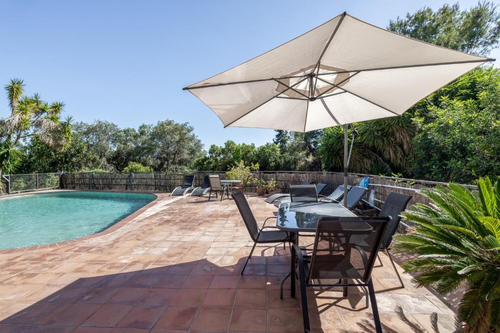 a patio with a table and an umbrella next to a pool at Apartamento I Els Cucons in Sant Pere de Ribes