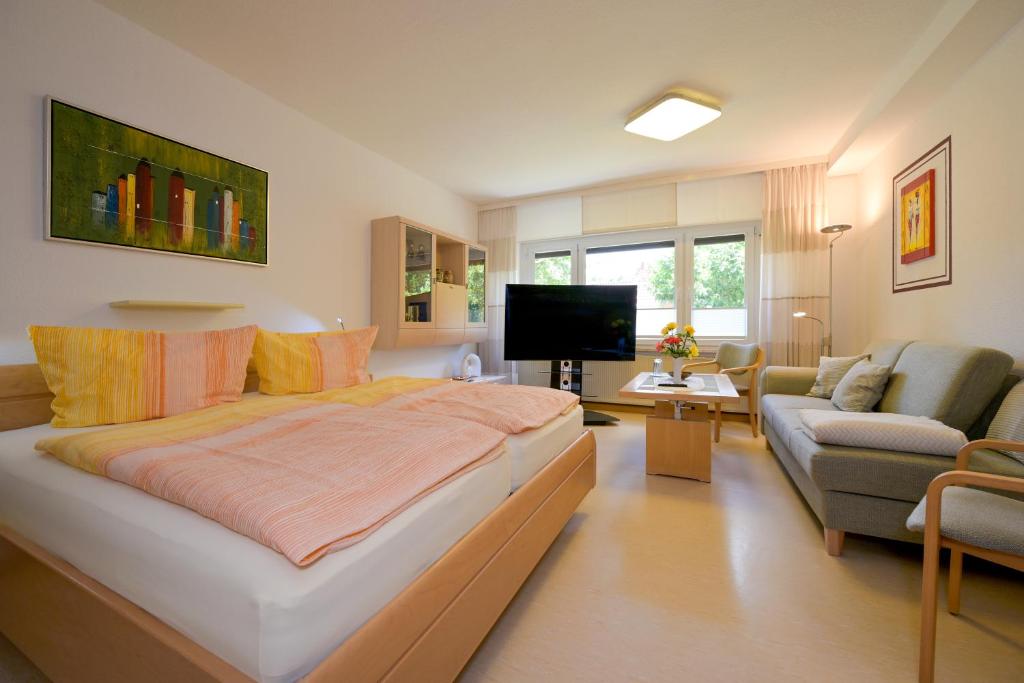 a bedroom with a large bed and a living room at Hotel Haus Orchideental Jena in Jena