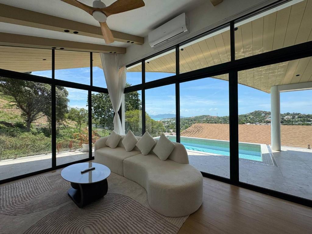 a living room with a white couch and large windows at Villa 7 Ocean View Pool Villa in Bophut