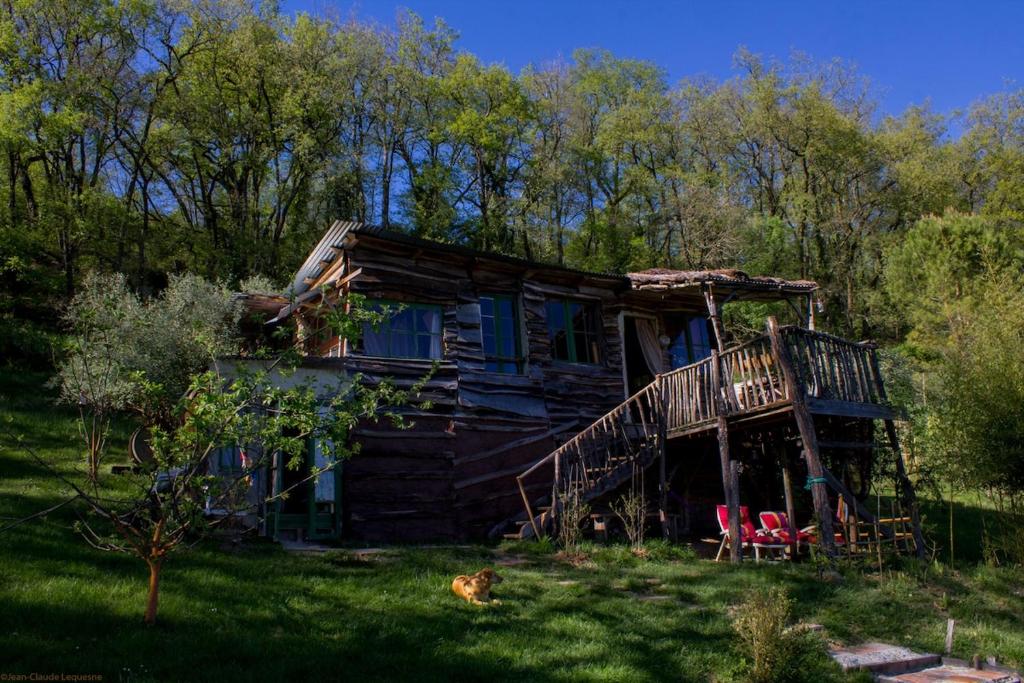 an old log cabin with a deck and a cat in front of it at Cabane Layénie sous les étoiles in Bajamont