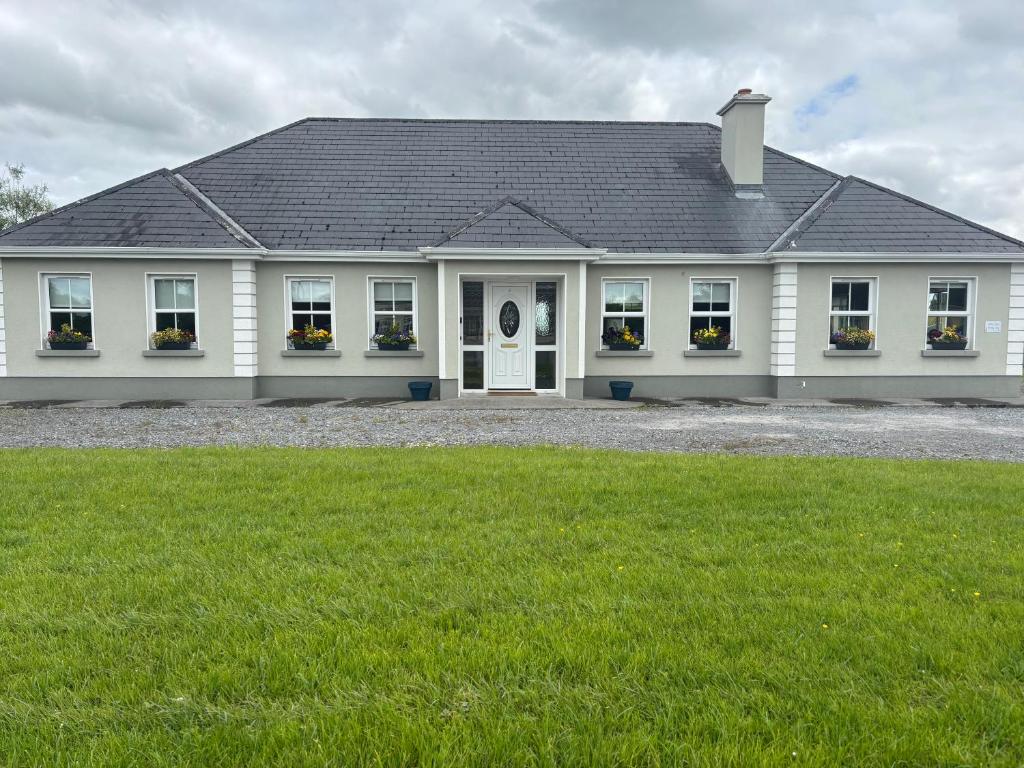 a white house with flowers in the windows at Albert Lock Bungalow 5 minute drive from Carrick in Carrick on Shannon