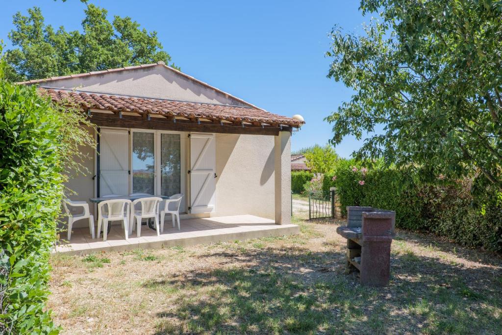 a cottage with a table and chairs in a yard at Le Micocoulier - La Fontinelle in Bessas