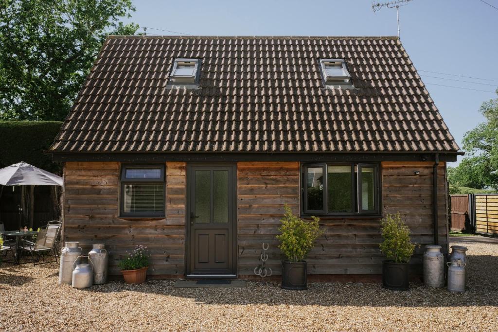 a small wooden house with a door and potted plants at Coach House in Milton Keynes