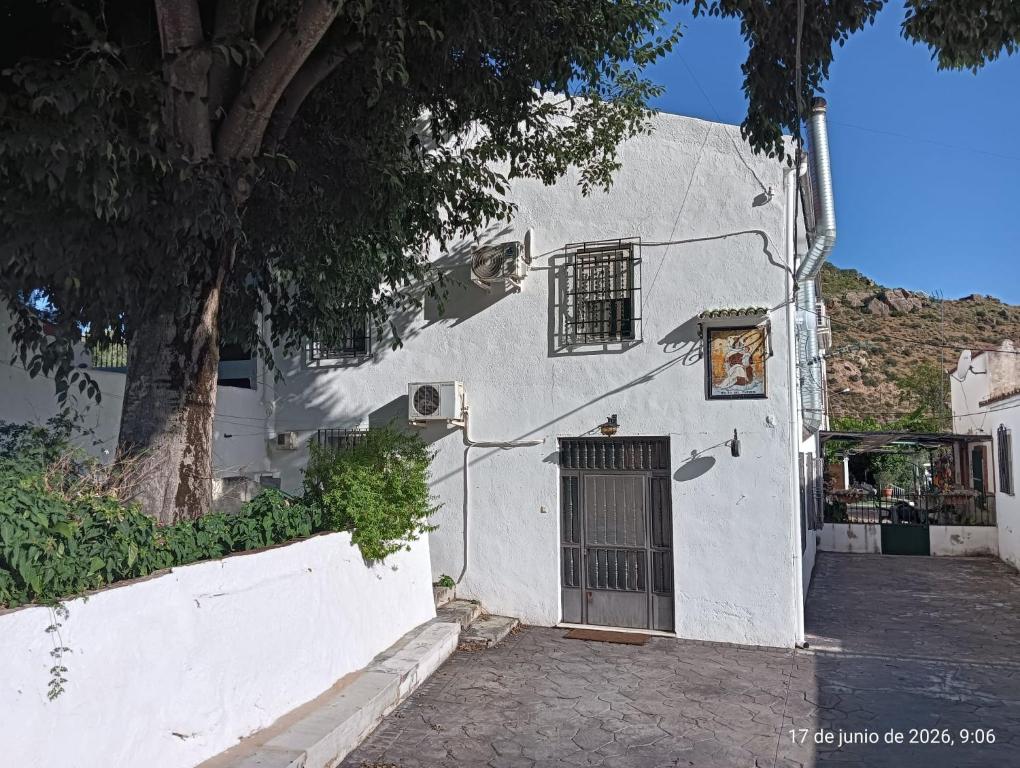 a white building with a door and a tree at Alojamiento Rural La Granja in La Cerradura