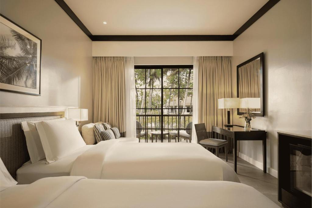 a bedroom with two beds and a desk and a window at Dusit Thani Lubi Plantation Resort in Kopiat
