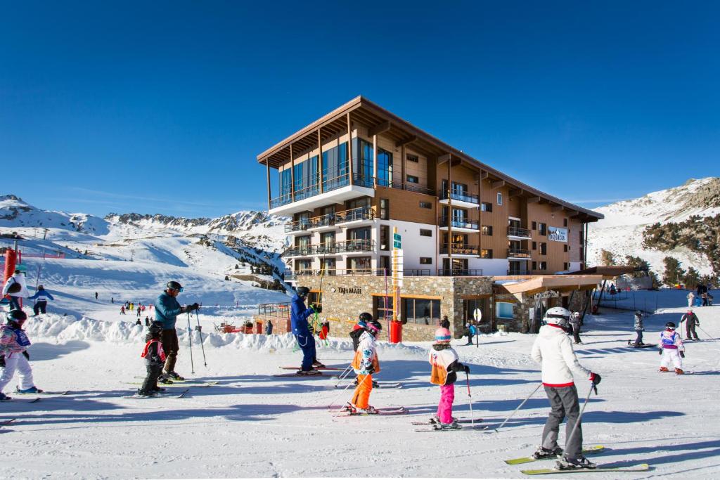 un gruppo di persone sugli sci di fronte a un rifugio di Hôtel Taj-I Mah by Les Etincelles ad Arc 2000