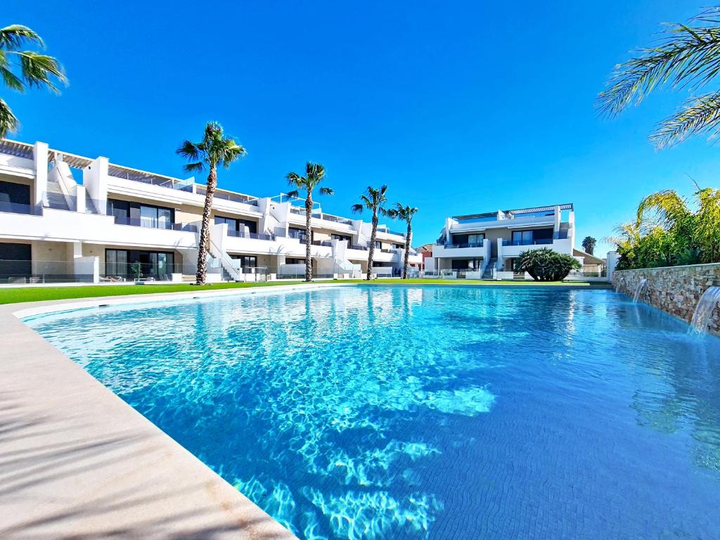 a swimming pool in front of a building with palm trees at La Llana Beach MDC - 8010 in Mar de Cristal