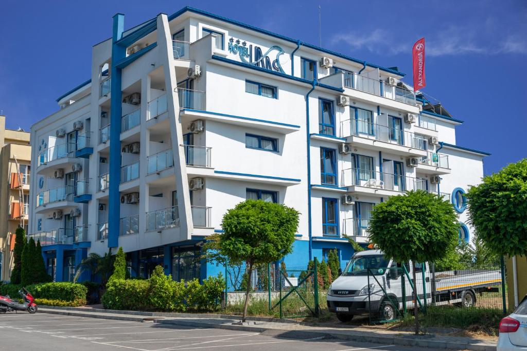 a white building with a van parked in front of it at Hotel Nadia in Primorsko
