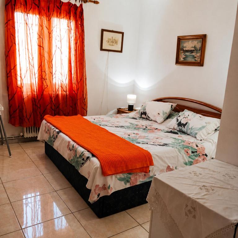 a bedroom with a bed with an orange blanket on it at Julia Country Home 200m from the Beach in Nea Plagia