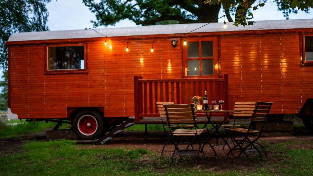an orange tiny house with a table and chairs at Schloss Sigrön Zirkuswagen in Bad Wilsnack