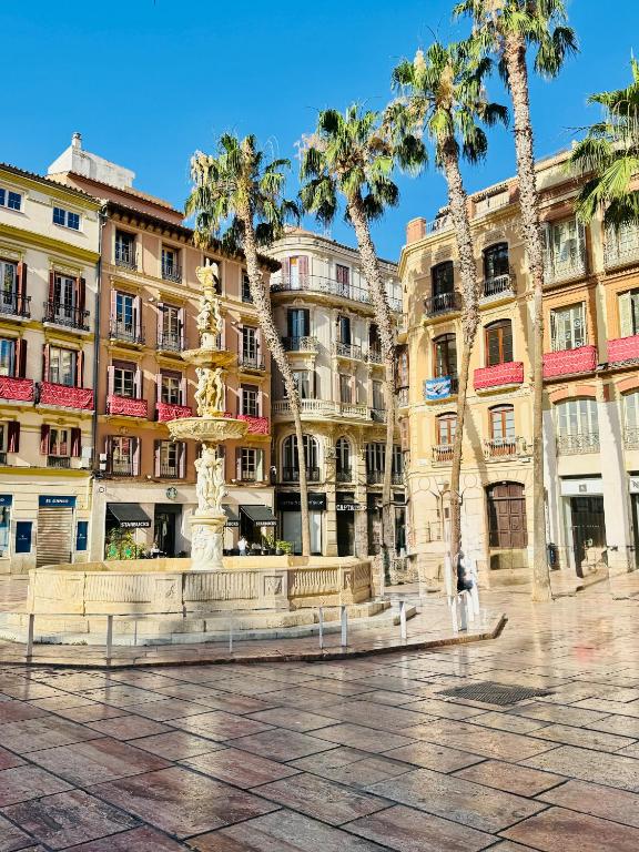 a fountain in front of a building with palm trees at Ático en Plaza de la Constitución 3 bedrooms in Málaga
