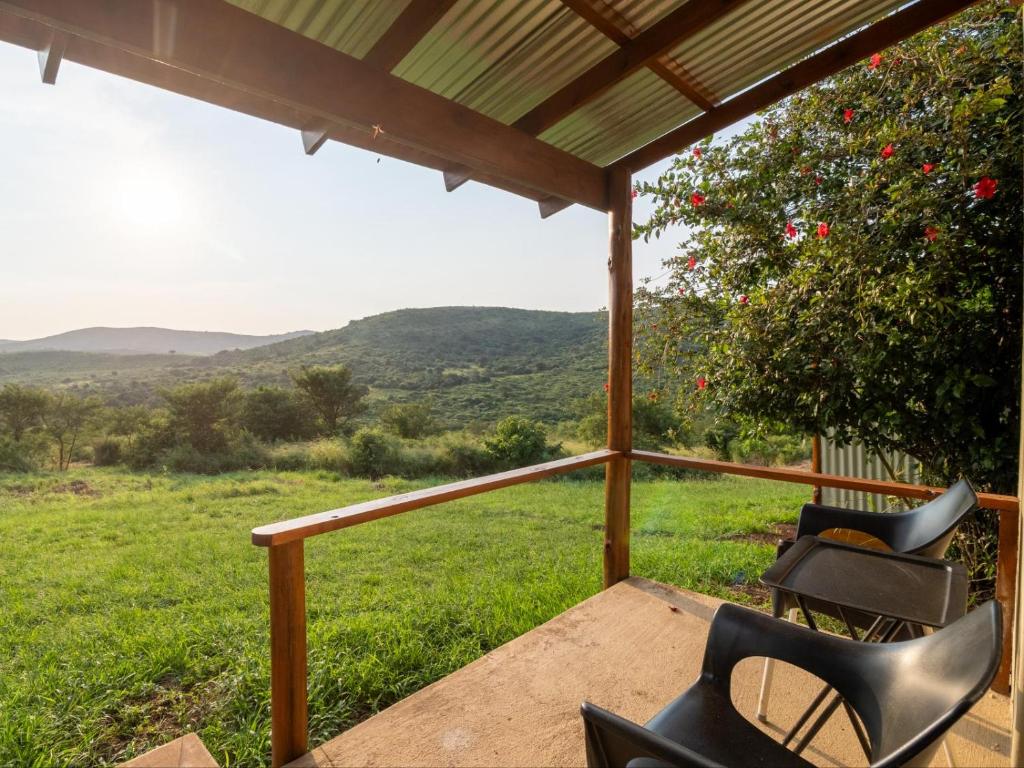 two chairs on a porch with a view of a field at Sunset Safari Camp at Hluhluwe Game Park in KwaNompondo