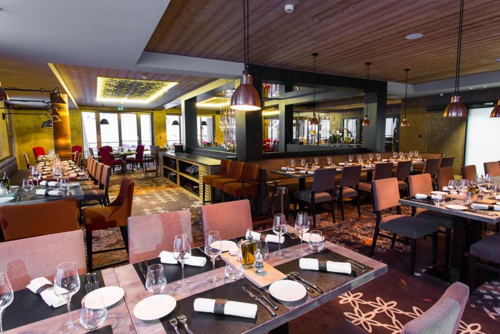 a restaurant with tables and chairs and a bar at Hôtel Taj-I Mah by Les Etincelles in Arc 2000