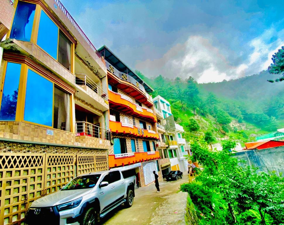 a white truck parked in front of a building at Redapple Rooms in Murree
