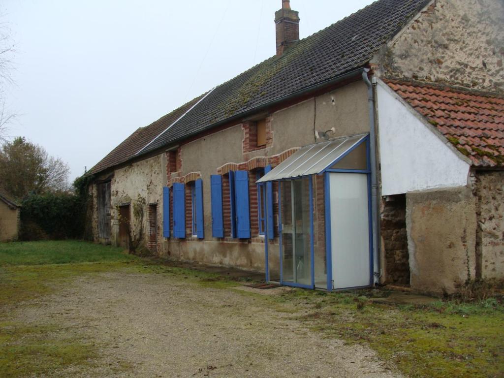 um velho edifício de pedra com persianas azuis em La Cerisaie em Ferreux