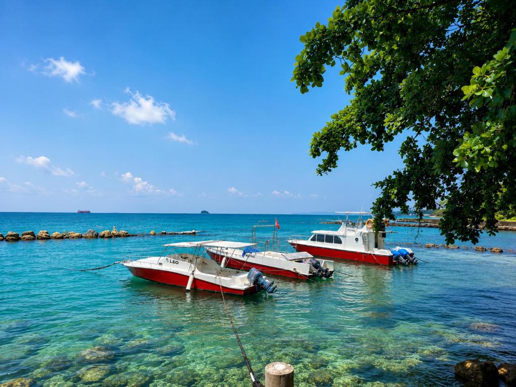 three boats are docked in the water near the shore at Allisa Resort Hotel in Anyer
