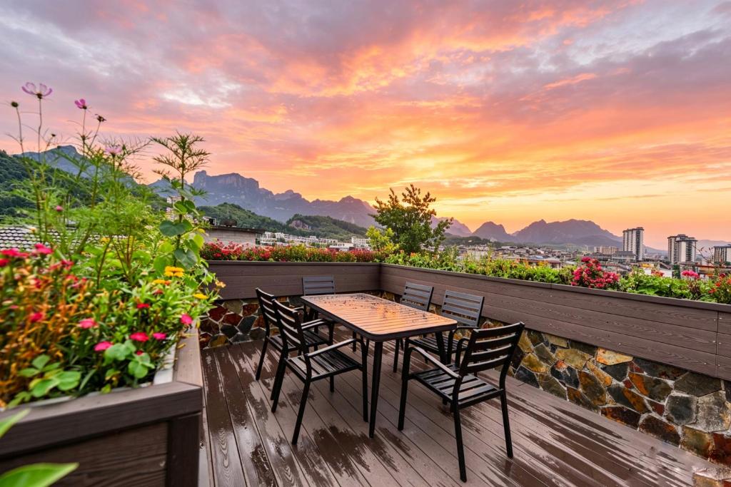 a table and chairs on a balcony with a sunset at Windmoon Hillcourt Tianmen Vis Lodge in Zhangjiajie