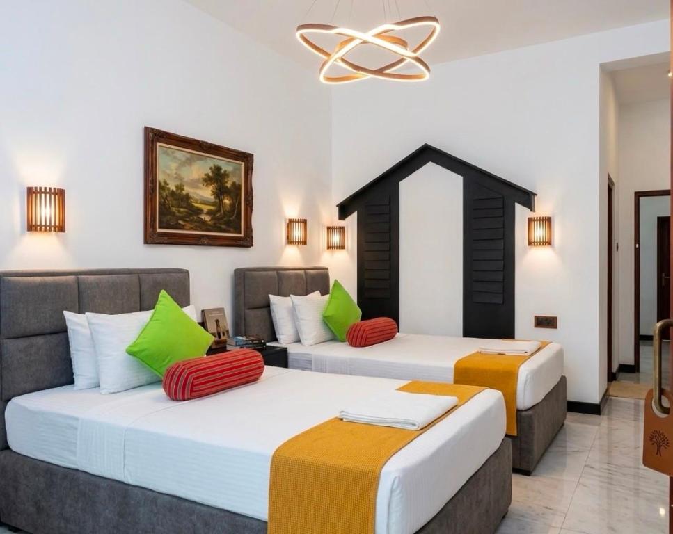 two beds in a hotel room with green and orange pillows at Sunshine Resort Sigiriya in Sigiriya