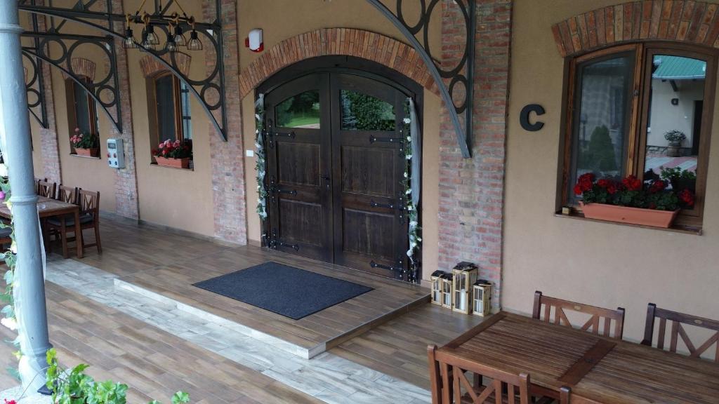 a porch with a wooden door and a table and chairs at Heritage Hall and More in Nagykálló