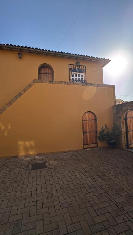 a yellow house with two doors and a patio at Curlt stays in Kampala