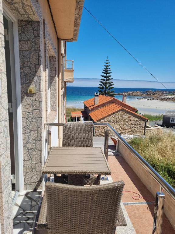a balcony with a table and chairs and the ocean at O Curro de Arou in Arou