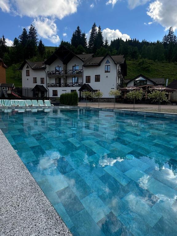 a swimming pool with blue water in front of a house at Villa Shale MarSo in Bukovel