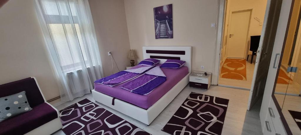 a bedroom with a purple bed and a chair at AMY APARTMAN in Tuzla