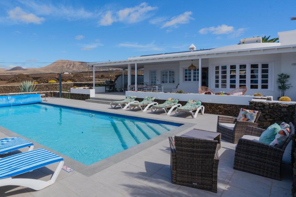 a house with a swimming pool and patio furniture at Villa Las Palmitas - Sea Views - Private Pool - Hot Tub - Table Tennis in Puerto Calero