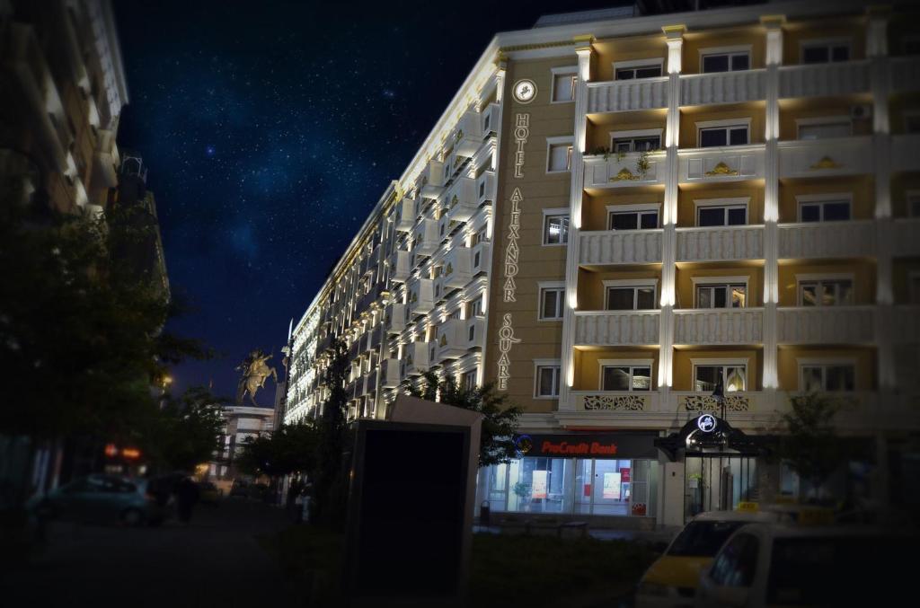a tall white building at night next to a street at Alexandar Square Boutique Hotel in Skopje