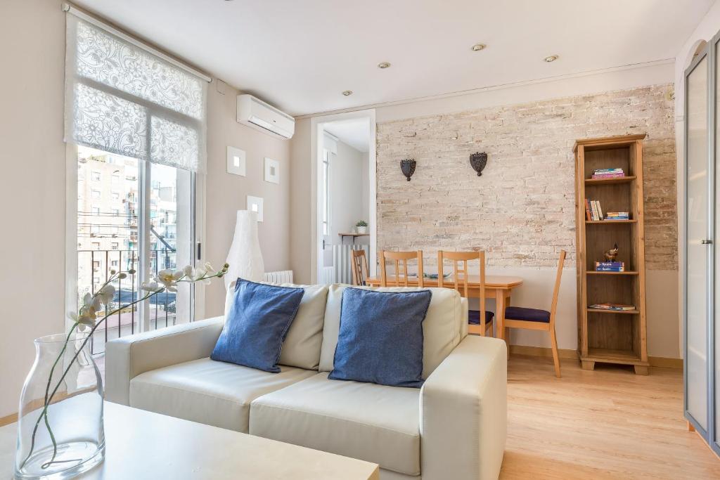 sala de estar con sofá blanco y pared de ladrillo en Apartment Link BCN Sagrada Familia, en Barcelona