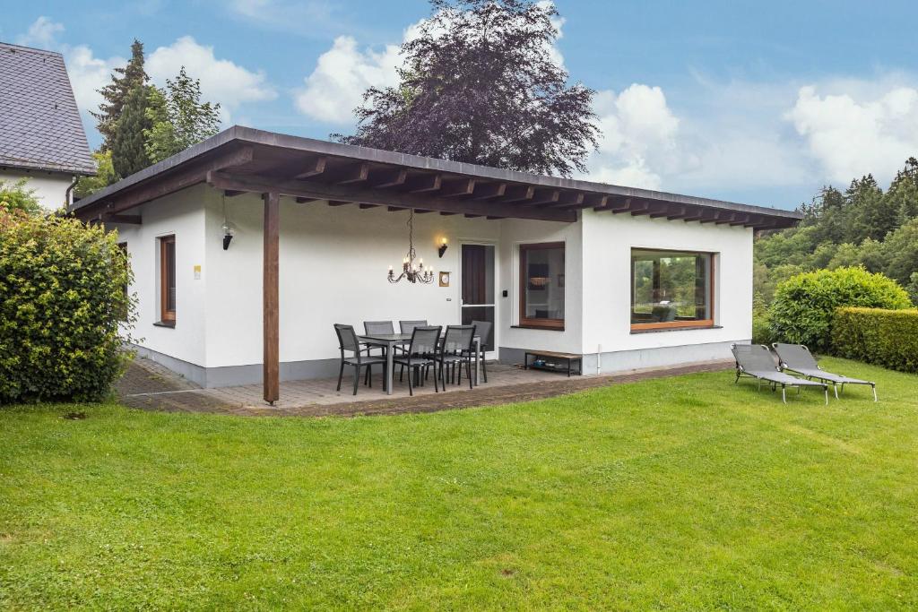a white house with a table and chairs in a yard at Ferienhaus Rothaarblick mit Sauna in Schmallenberg