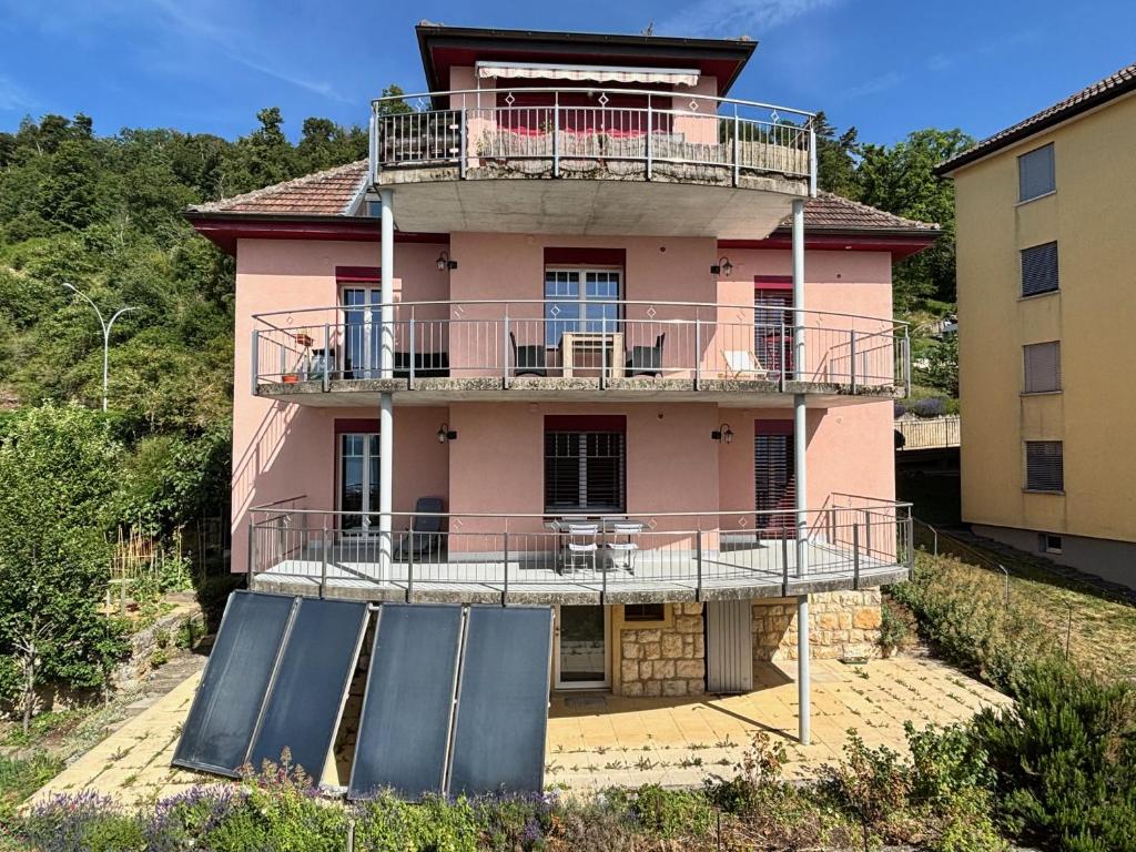 a pink house with a balcony and a ramp at Chez Carole (4 pièces) in Neuchâtel