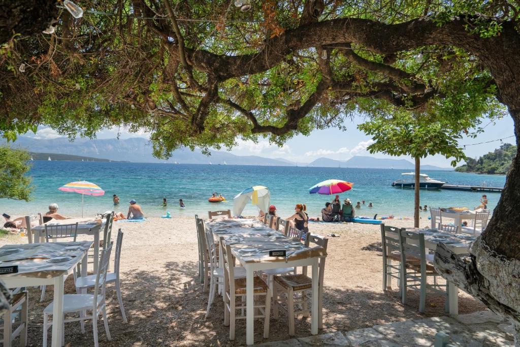 a beach with tables and chairs and people on the beach at Odysseia Beachside Apartments in Nikiana