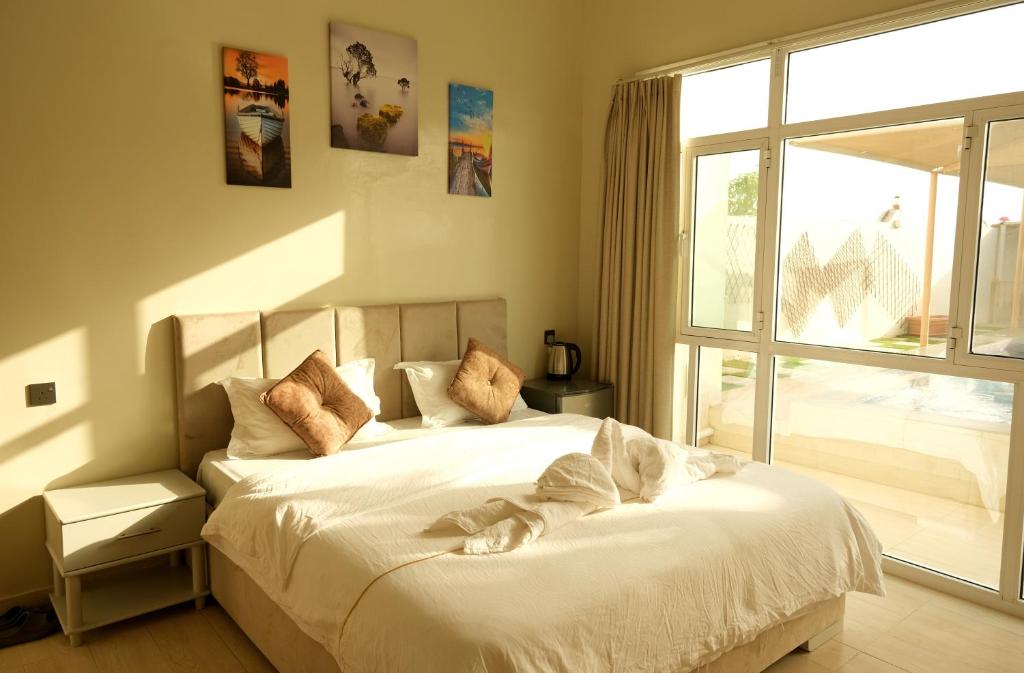 a bedroom with a bed with white sheets and a window at Sea Turtles Guest House in Al Ḩadd