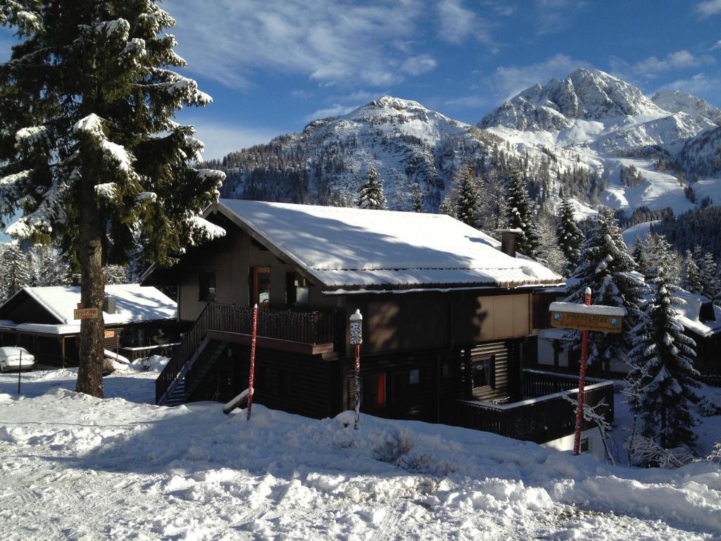 a cabin in the snow with mountains in the background at Haus Petra in Sonnenalpe Nassfeld