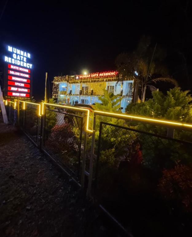 a building with a lit up sign in the night at Munnar Gate Residency in Pooppara