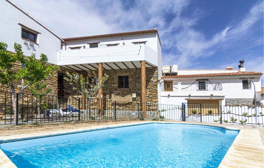a villa with a swimming pool in front of a house at Matasiete in Laroya