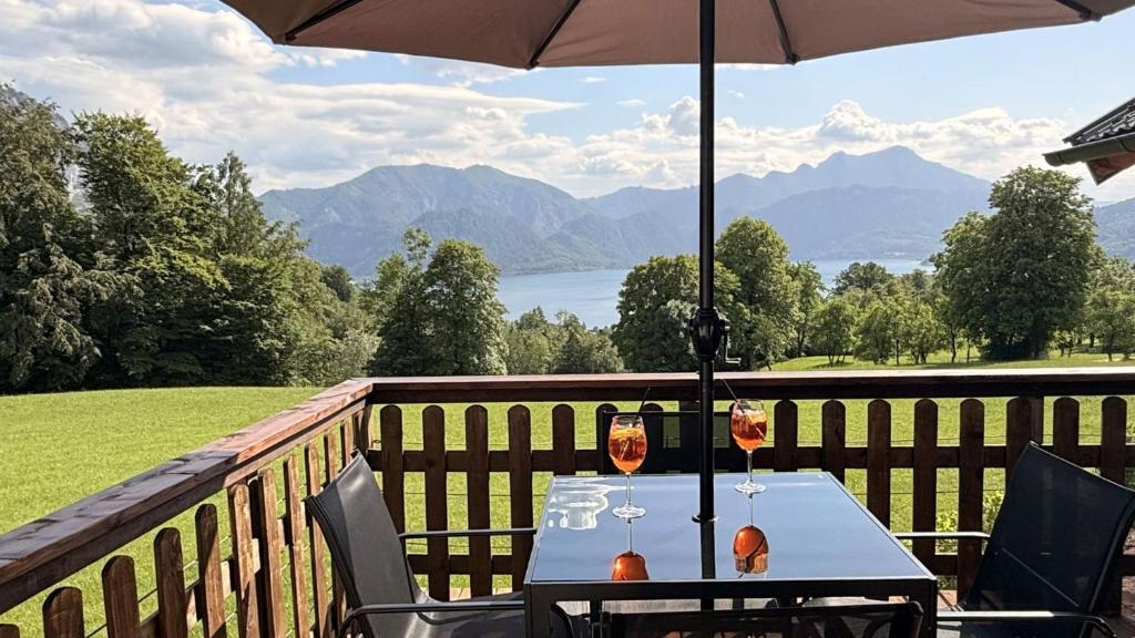 a table with two wine glasses and an umbrella on a balcony at Attersee Panorama Apartments in Steinbach am Attersee