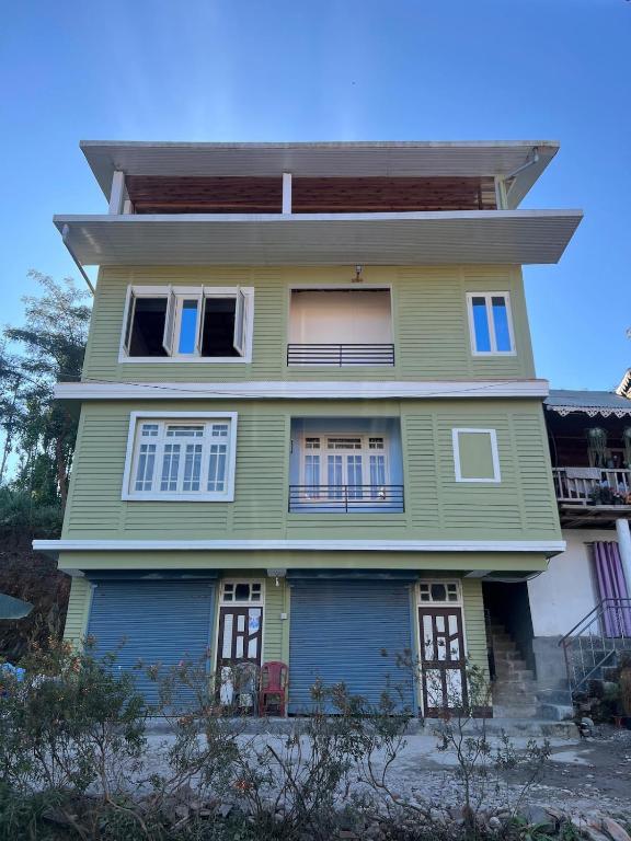 a green house with white windows on the side of it at Home away homestay in Namchi