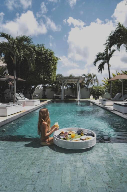 a little girl sitting in a swimming pool with a tray of food at White Palm Uluwatu - Wellness & Recovery Retreat - 2 Min Walk to Balangan Beach in Jimbaran
