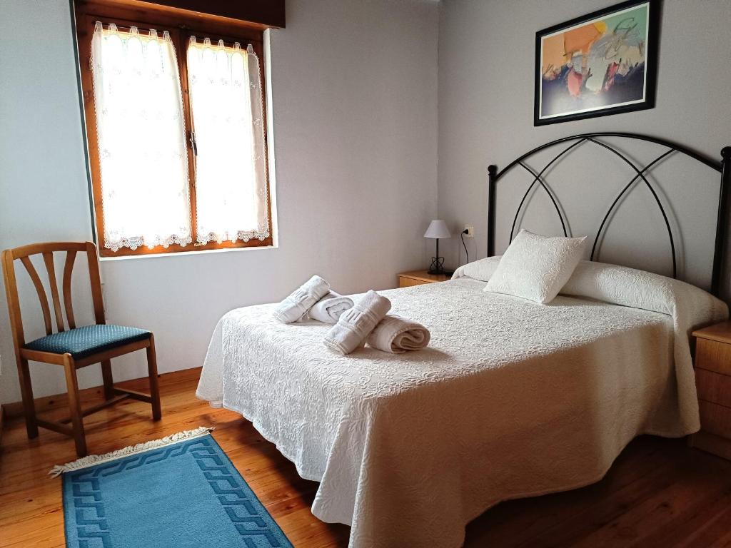 a bedroom with two beds and a chair and a blue rug at Casa con patio en Nueva de Llanes - El Churru in Nueva de Llanes