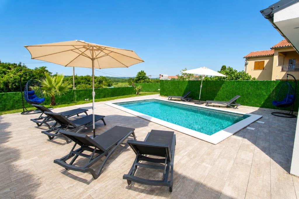 a swimming pool with chairs and an umbrella next to a pool at Villa Riviera in Nedeščina