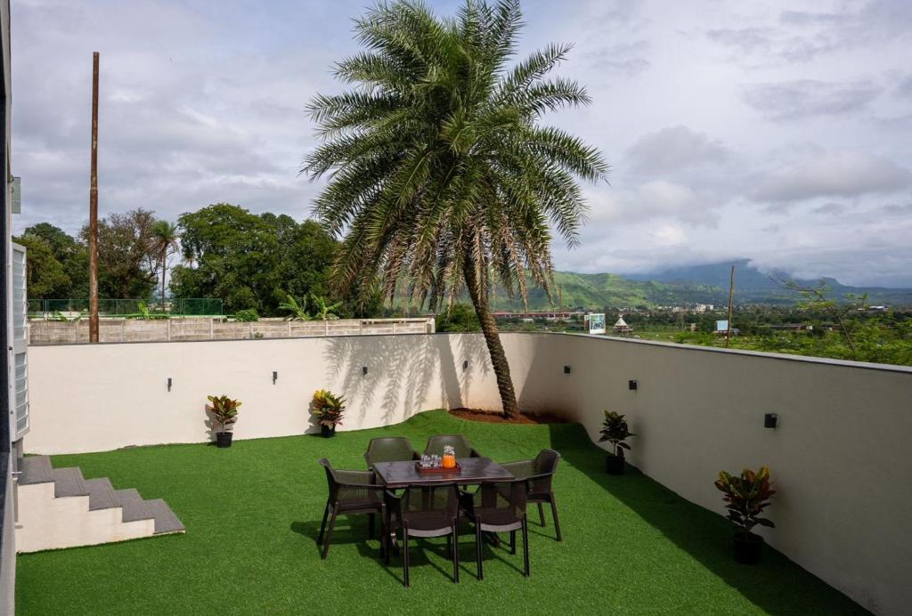 a patio with a table and a palm tree at Evara Sky Jacuzzi Villa in Igatpuri