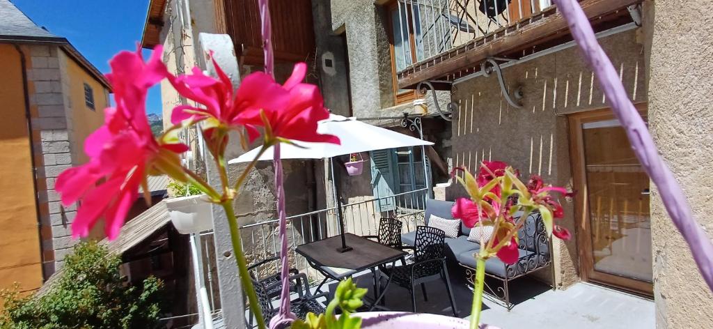 a balcony with a table and chairs and an umbrella at Maison à Tour Briançon in Briançon
